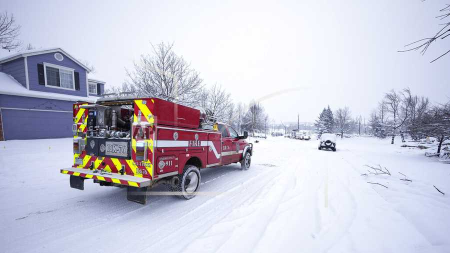 A fire truck moves along a road separating burned homes from those spared by a pair of wildfires Saturday, Jan. 1, 2022, in Superior, Colo. An overnight dumping of snow and frigid temperatures compounded the misery of hundreds of Colorado residents who started off the new year trying to salvage what remains of their homes after a wind-whipped wildfire tore through the Denver suburbs. (AP Photo/David Zalubowski)