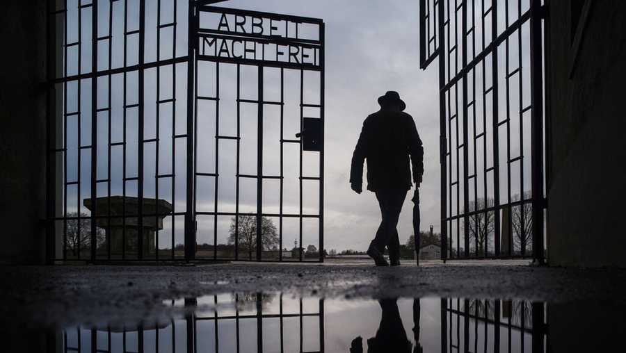 In this Sunday, Jan. 27, 2019 file photo a man walks through the gate of the Sachsenhausen Nazi death camp with the phrase 'Arbeit macht frei' (work sets you free) during International Holocaust Remembrance Day in Oranienburg, about 30 kilometers (18 miles), north of Berlin, Germany. German prosecutors say they have charged a 100-year-old man with 3,518 counts of accessory to murder on allegations he served as an SS guard at the Nazis’ Sachsenhausen concentration camp on the outskirts of Berlin. (AP Photo/Markus Schreiber, file)