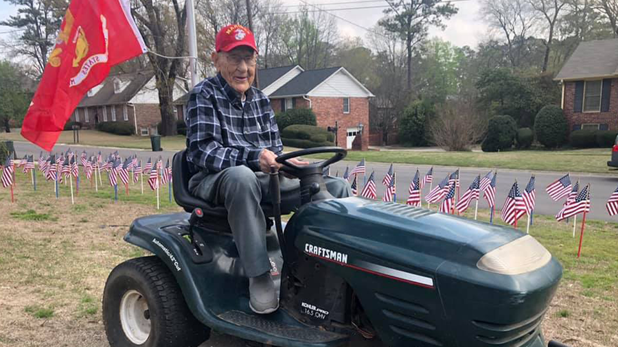 Colonel Carl Cooper of Vestavia Hills, Ala. mowing his yard with a USMC flag on the lawn mower and dozens of American flags in the yard.