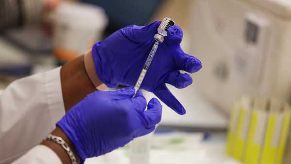 Close-up photo of gloved hands holding a Pfizer COVID-19 vaccine booster shot, administered as the Mount Sinai South Nassau Vaxmobile vists Freeport High School, in Freeport, New York on Nov. 30, 2021.