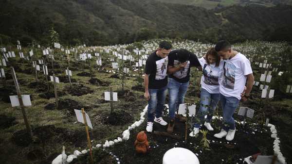 Relatives of Luis Enrique Rodriguez, who died of COVID-19, visit where he was buried on a hill at the El Pajonal de Cogua Natural Reserve, in Cogua, north of Bogota, Colombia, Monday, Oct. 25, 2021. Rodriguez died May 14, 2021. Relatives bury the ashes of their loved ones who died of coronavirus and plant a tree in their memory.