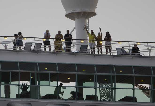 Passengers wave as the Royal Caribbean Freedom of the Seas gets underway through the Government Cut shipping channel at PortMiami during the first U.S. trial cruise testing COVID-19 protocols on June 20, 2021 in Miami, Florida. The cruise ship will get underway with employee volunteers on board. According to the cruise line, the purpose of the simulated voyage is to observe its “multilayered health and safety measures” following CDC requirements. The trial is one more step in the process of resuming operations out of U.S. ports, 15 months after the pandemic caused the cruise industry to shut down.