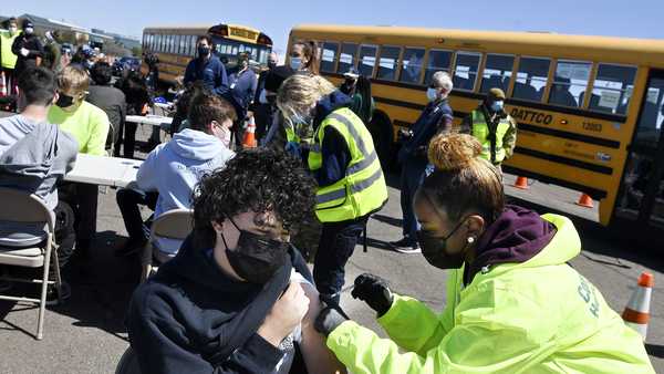 In this April 26, 2021, file photo, CREC Academy of Aerospace and Engineering sophomore Brian Acevedo, 16, receives a COVID-19 vaccine from nurse Myra Glass, of East Hartford, during a mass vaccination site at Pratt & Whitney Runway in East Hartford, Conn.