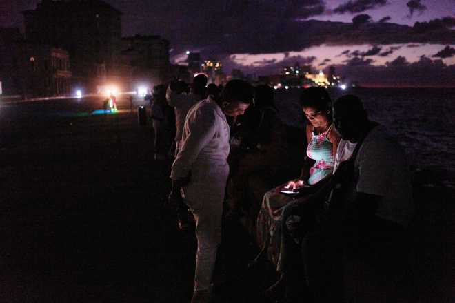 People spend the night in the dark on the Malecon during a blackout in Havana, Cuba, Saturday, March 21, 2026.