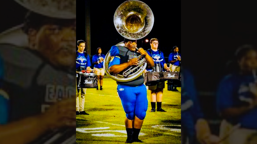 Football player playing a tuba with a band
