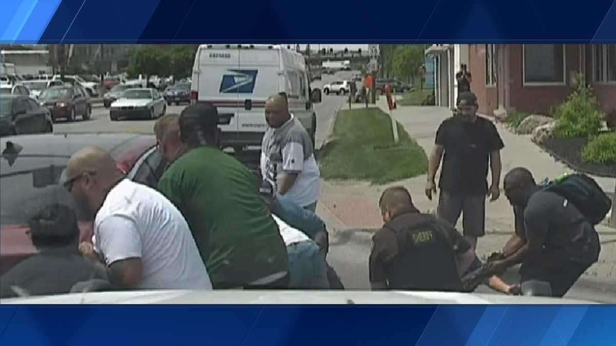 Group of bystanders lift vehicle off of man stuck after crash