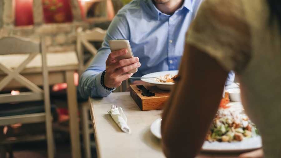 File photo: Man checking messages while having dinner in a restaurant