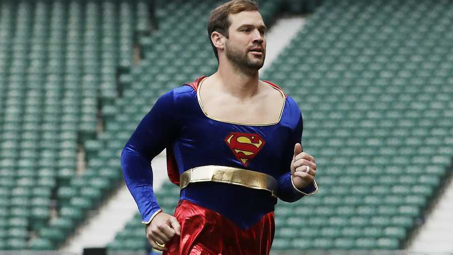 Arizona Cardinals quarterback Drew Stanton does a somersault on the field dressed as "Supergirl" before an NFL football game against Los Angeles Rams at Twickenham Stadium in London, Sunday Oct. 22, 2017. 