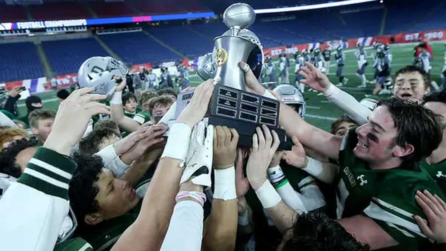 Duxbury's Matthew Festa and the rest of the Dragons celebrate with their newly earned trophy after beating Grafton 42-7 in the Division 4 Super Bowl at Gillette Stadium in Foxborough, Massachusetts, on Friday, Dec. 2, 2022.