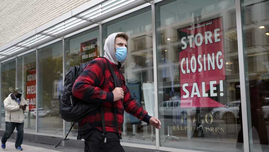 A passer-by walks past a store closing sign, right, in the window of a department store, Tuesday, Oct. 27, 2020, in Boston. Americans may feel whiplashed by a report Thursday, Oct. 29, on the economy's growth this summer, when an explosive rebound followed an epic collapse. The government will likely estimate that the economy grew faster on an annualized basis last quarter than in any such period since record-keeping began in 1947.