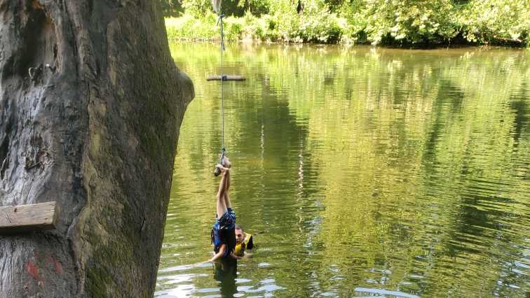 Boy tangled up upside-down on rope swing above water rescued