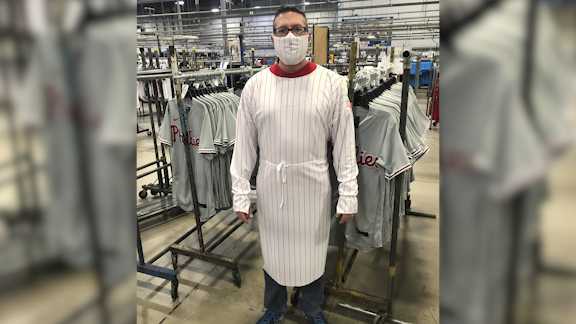 This image provided by Fanatics, shows a model wearing a protective mask and gown for medical professionals made from the fabric of a baseball uniform. Fanatics, the company that manufactures uniforms for Major League Baseball in Pennsylvania, has suspended production on jerseys and is instead using the polyester mesh fabric to make masks and gowns that help fill the dearth of protective wear at hospitals in Pennsylvania and nearby states.