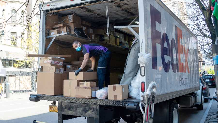 FILE: A FedEx employee wearing a protective mask and gloves loads boxes into a truck amid the coronavirus pandemic on April 28, 2020 in New York City, United States. FedEx is planning to hire 70,000 workers as it gears up for the 2020 holiday season. The multinational delivery service says the majority of new hires will be seasonal employees.