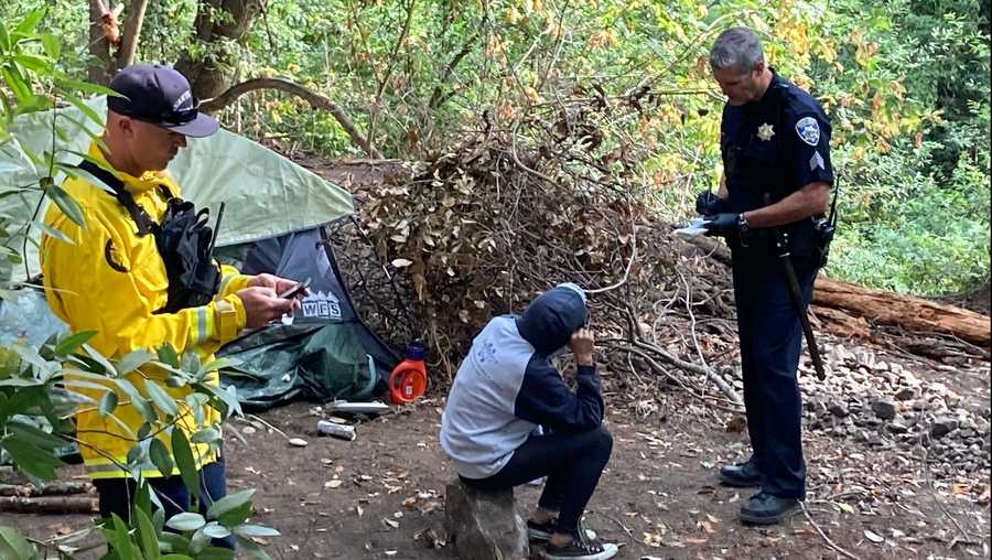 a firefighter and a police officer talk to an illegal camper at sycamore grove in santa cruz, july 29