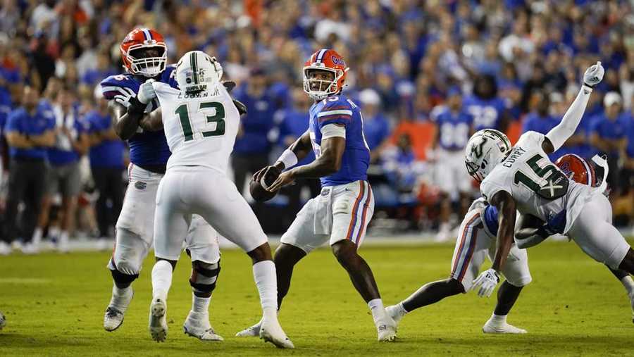 florida quarterback anthony richardson, center, looks for a receiver as south florida defensive end tramel logan (13) and defensive back jayden curry (15) rush during the first half of an ncaa college football game, saturday, sept. 17, 2022, in gainesville, fla. (ap photo/john raoux)