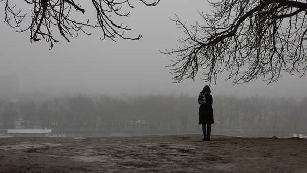 Girl standing alone in the park on gloomy day.