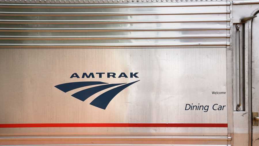 LAMY, NEW MEXICO - MAY 19, 2019: The Amtrak logo on the side of the dining car of an Amtrak train stopped at the railroad depot in Lamy, New Mexico, near Santa Fe. Amtrak&apos;s Southwest Chief, which transports passengers between Chicago and Los Angeles, makes daily stops at the small Lamy station to pick up and discharge passengers.