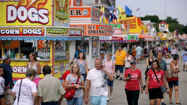 Fairgoers walk past the food venders lining Grand Avenue at the Iowa State Fair on Aug. 08, 2019, in Des Moines.