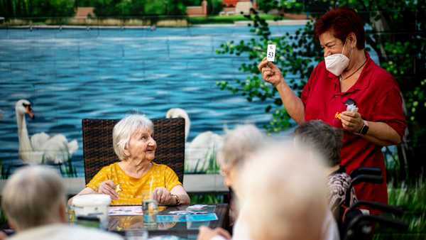 Brandenburg, Neuruppin: Resident Johanna Muschel (back, l) looks at Marion Wodetzki (r), caregiver, holding up a bingo card during a bingo tournament. (Photo by Fabian Sommer/picture alliance via Getty Images)