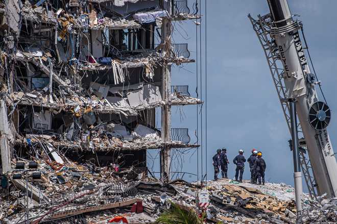 Members of the South Florida Urban Search and Rescue team look for possible survivors in the partially collapsed 12-story Champlain Towers South condo building on June 27, 2021 in Surfside, Florida.