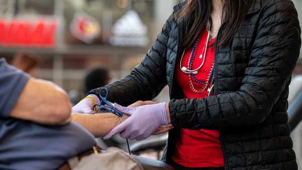 A phlebotomist tends to the arm of a blood donor. (Photo by Jon Cherry/Getty Images)