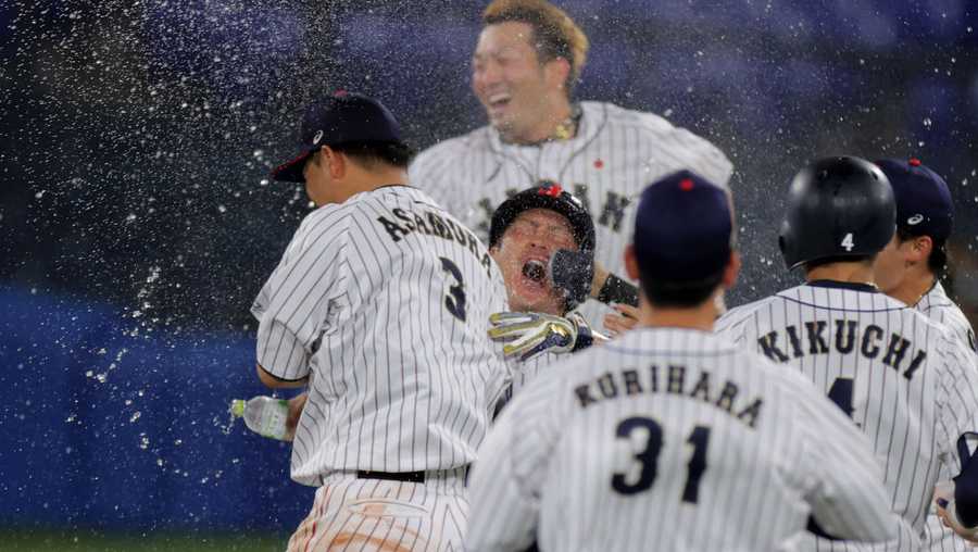 Japan&apos;s Takuya Kai (middle 2nd L) is celebrated his walk-off RBI single by spraying water from teammates during the extra tenth inning of the Tokyo 2020 Olympic Games baseball round 2 game between USA and Japan at Yokohama Baseball Stadium in Yokohama, Japan, on August 2, 2021. (Photo by KAZUHIRO FUJIHARA / AFP) (Photo by KAZUHIRO FUJIHARA/AFP via Getty Images)