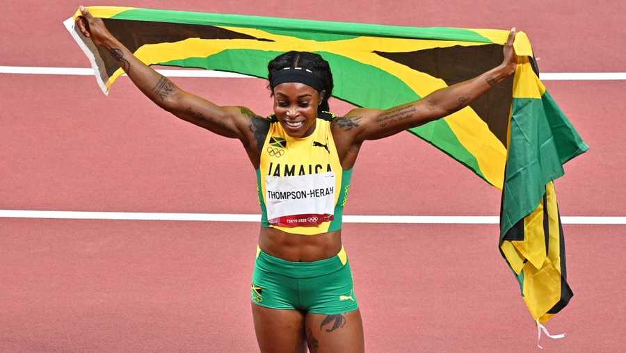 Jamaica&apos;s Elaine Thompson-Herah celebrates with the flag of Jamaica after winning the women&apos;s 200m final during the Tokyo 2020 Olympic Games at the Olympic Stadium in Tokyo on August 3, 2021. (Photo by Philip FONG / AFP) (Photo by PHILIP FONG/AFP via Getty Images)