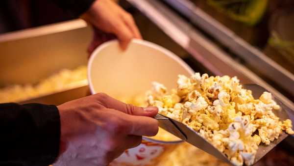 10 September 2022, Berlin: ILLUSTRATION - An employee at Cinestar Treptow fills a bucket with popcorn. Numerous movie theaters throughout Germany are offering reduced admission prices of five euros per screening on Saturday and Sunday. Photo: Fabian Sommer/dpa (Photo by Fabian Sommer/picture alliance via Getty Images)