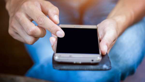 Close up of a woman hand using a smart phone on a desk at home