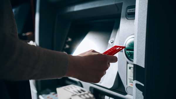 Close up of young woman inserting her bank card into automatic cash machine in the city. Withdrawing money, paying bills, checking account balances, transferring money. Privacy protection, internet and mobile security concept