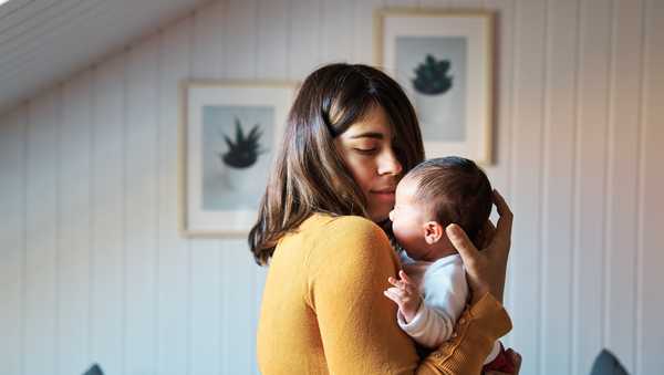 Side view of new mother comforting her newborn while crying. Baby getting used to noises and lights in her first days of life outside the womb.