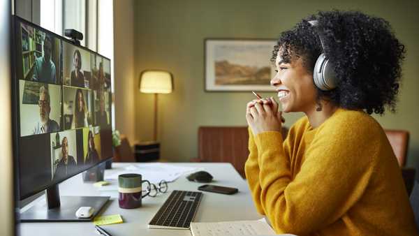 Businesswoman with headphones smiling during video conference. Multiracial male and female professionals are attending online meeting. They are discussing business strategy.