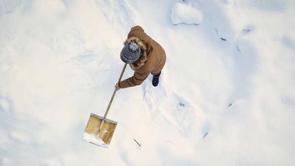 person cleaning snow with snow shovel in winter