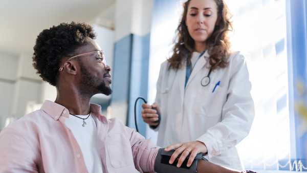 the man is attended to by a doctor who is checking his blood pressure.