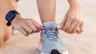 Close-up view of female jogger hands tying laces of her sport shoes before running exercise routine. Motivation, healthy lifestyle and fitness concept.