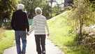 Rear view of active senior couple holding hands while walking in park