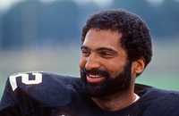 Running back Franco Harris of the Pittsburgh Steelers smiles as he looks on from the field during summer training camp at St. Vincent College in July 1982 in Latrobe, Pennsylvania.