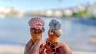 Woman and man hands holding colorful two ice cream waffle cone in hands on summer season, sea background