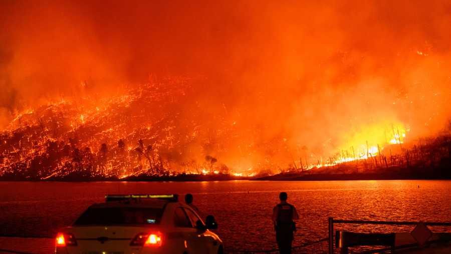 TOPSHOT - Law enforcement members watch as the Thompson fire burns over Lake Oroville in Oroville, California on July 2, 2024. A heatwave is sending temperatures soaring resulting in red flag fire warnings throughout the state. (Photo by JOSH EDELSON / AFP) (Photo by JOSH EDELSON/AFP via Getty Images)