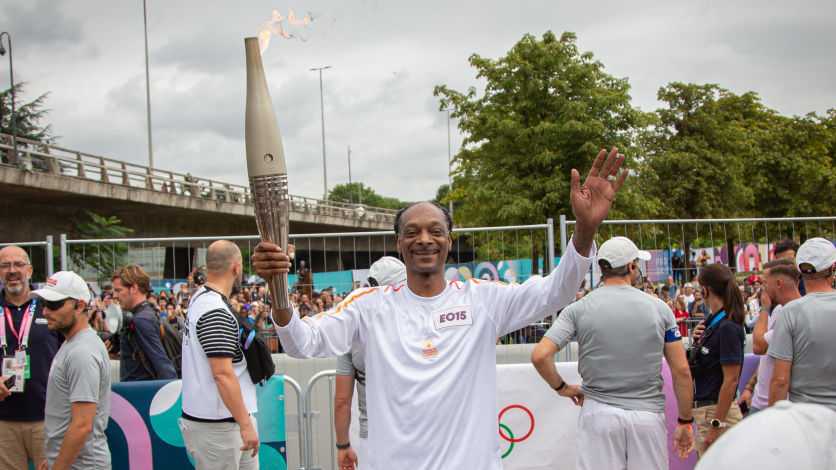 Rapper Snoop Dog carries the Olympic flame during the last stage of the Olympic torch before the Olympic Games 2024 opening ceremony in Seine-Saint-Denis, France on July 26, 2024 (Photo by Victoria Valdivia / Hans Lucas / Hans Lucas via AFP) (Photo by VICTORIA VALDIVIA/Hans Lucas/AFP via Getty Images)