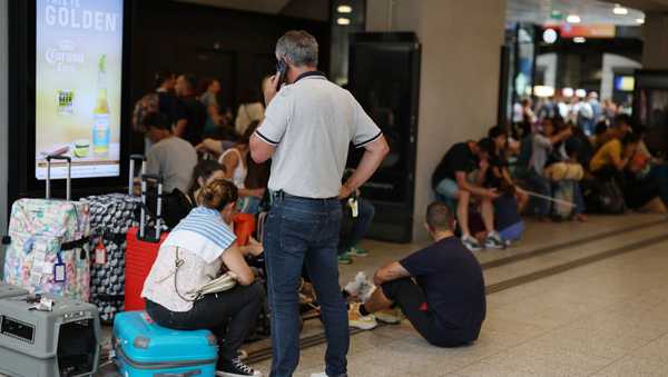 Passengers remain sat while waiting at Gare de Montparnasse after damage to high-speed rail lines caused delays and cancellations on July 26, 2024 in Paris, France.
