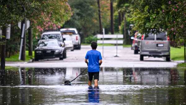A man walks on a flooded street due to Tropical Storm Debby on August 06, 2024 in Charleston, South Carolina.