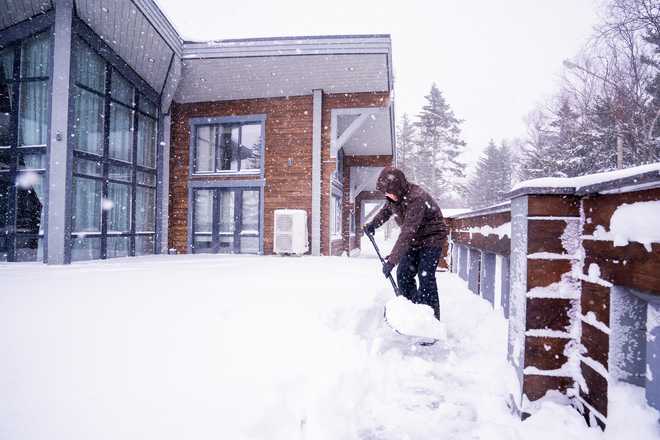 A man cleans the area of ​​his house after a snowstorm.