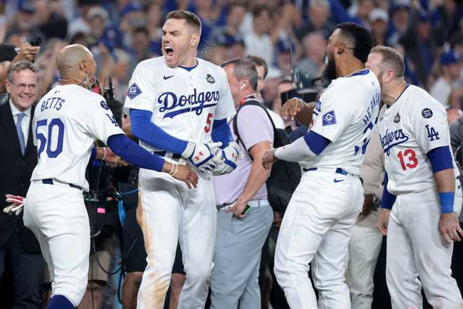 LOS ÁNGELES, CA - 25 de octubre de 2024: El primera base de los Dodgers de Los Ángeles, Freddie Freeman (5), celebra con sus compañeros de equipo después de conectar un jonrón de grand slam en la décima entrada. Viernes octubre. Juego 1 de la Serie Mundial contra los Yankees en el Dodgers Stadium de Los Ángeles. 25. 2024. (Wally Scalidge/Los Angeles Times vía Getty Images)