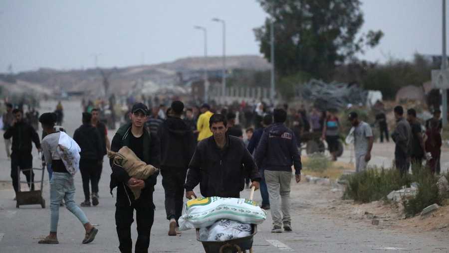 Palestinians carry humanitarian aid back from a distribution point in the Bureij camp for Palestinian refugees in the central Gaza Strip early on June 9, 2025. (Photo by Eyad BABA / AFP)