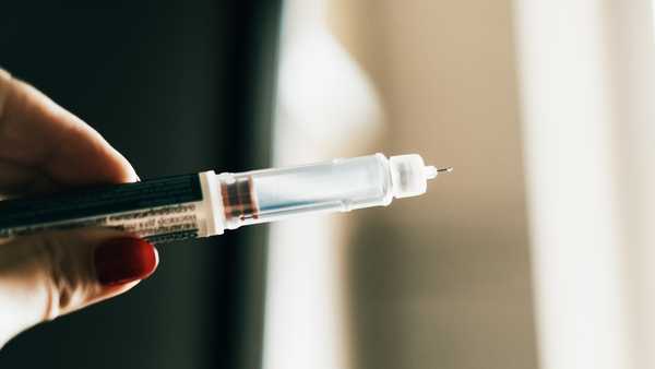 A detailed view of a syringe device being held in a hand, ready for use.