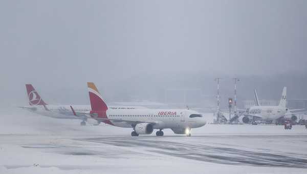 08 January 2026, Hamburg: Two airplanes are on the snow-covered runway at Hamburg Airport.