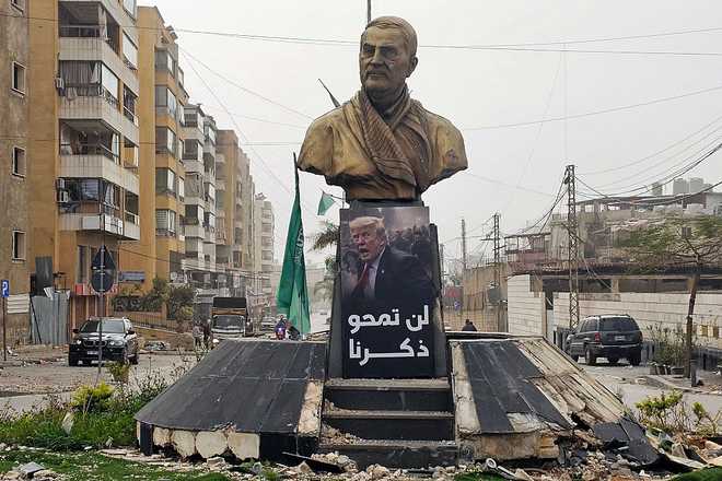 A sign depicting US President Donald Trump, with the caption "you will not erase our memory" in Arabic, is displayed before a memorial depicting Qassem Soleimani, the slain commander of the "Quds Force" of Iran's Islamic Revolutionary Guards Corps (IRGC) who was killed by a US airstrike in 2020, along the road leading to Beirut International Airport in Beirut on April 4, 2026. Lebanon was drawn into the Middle East war on March 2 when Hezbollah launched attacks on Israel to avenge the killing of the Iranian leader. Israel has responded with broad strikes across Lebanon and a ground offensive. (Photo by AFP via Getty Images)