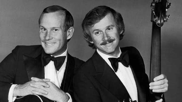 1976:  Studio portrait of American comedy duo, the Smothers Brothers (Tom (L) and Dick Smothers,) wearing tuxedos and holding guitars.  (Photo by Hulton Archive/Getty Images)