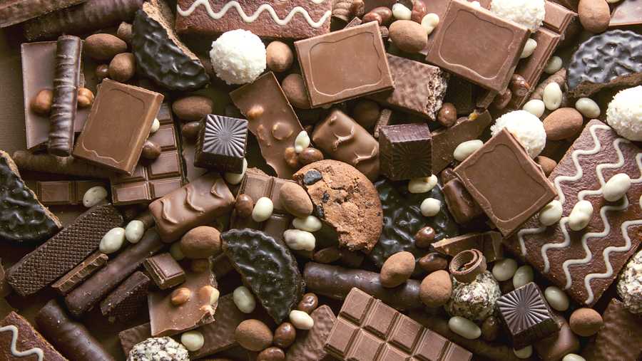 Chocolate background. Many pieces of chocolate, candies, cookies, biscuits, cakes and other sweets. Milk chocolate and dark chocolate. coconut candy